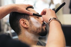 Young Bearded Man Getting Beard Haircut With A Razor By Barber. Barbershop Theme