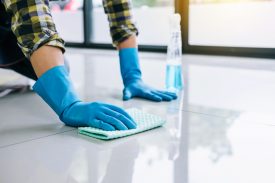 Husband housekeeping and cleaning concept, Happy young man in blue rubber gloves wiping dust using a spray and a duster while cleaning on floor at home. (Husband housekeeping and cleaning concept, Happy young man in blue rubber gloves wiping dust usin
